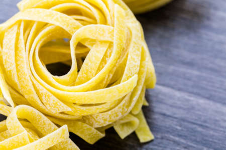 Organic fettuccine nests pasta on wood board.の写真素材