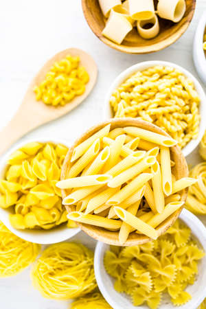 Variety of yellow dry pasta in small round bowls.の写真素材