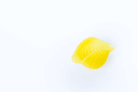 Organic yellow shell pasta on a white background.の写真素材