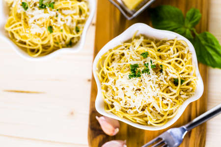 Cheese and pepper spaghetty with green garnish in white bowls.の写真素材