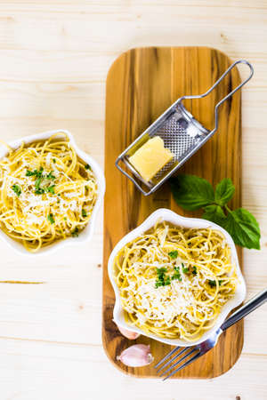 Cheese and pepper spaghetty with green garnish in white bowls.の写真素材
