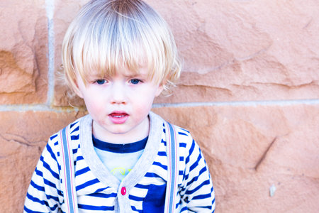 Cute toddler boy posing for camera in the city.