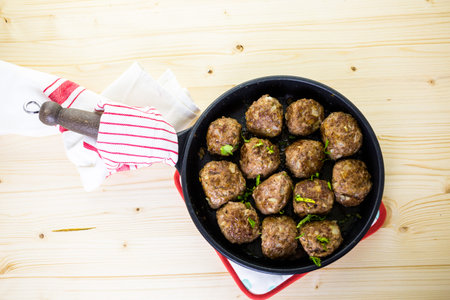 Frying large homemade Italian meatballs on a midium frying pan for dinner.