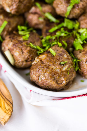 Serving large Italian meatballs in a white serving dish for dinner.