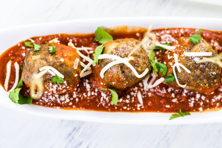 Large Italian meatballs garnished with cilantro and parmesan cheese as appetisers.の写真素材