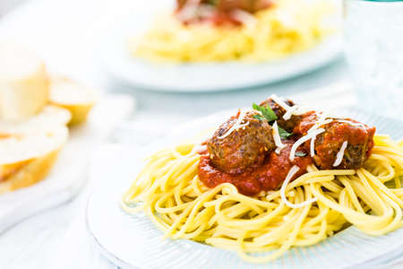 Homemade Italian meatballs garnished with cilantro and parmesan cheese over spaghetti for dinner.の写真素材
