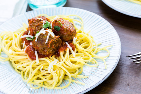 Homemade Italian meatballs garnished with cilantro and parmesan cheese over spaghetti for dinner.の写真素材