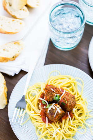 Homemade Italian meatballs garnished with cilantro and parmesan cheese over spaghetti for dinner.の写真素材
