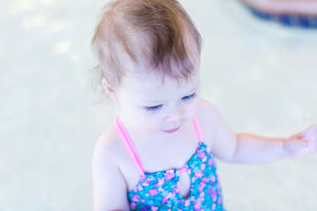 Cute baby girl swimming at indoor swimming pool.の写真素材