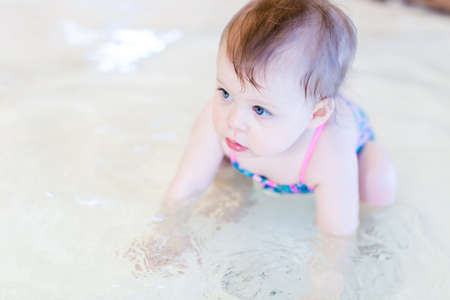 Cute baby girl swimming at indoor swimming pool.の写真素材