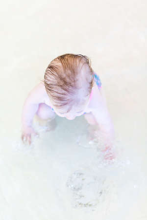 Cute baby girl swimming at indoor swimming pool.の写真素材
