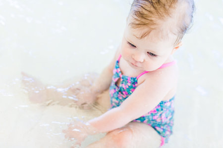 Cute baby girl swimming at indoor swimming pool.の写真素材