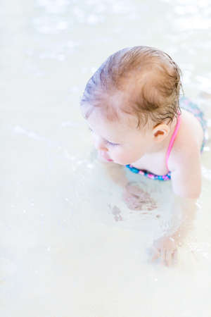 Cute baby girl swimming at indoor swimming pool.の写真素材