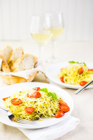 Homemade angel hair pasta with pesto sauce and roasted cherry tomatoes.の写真素材