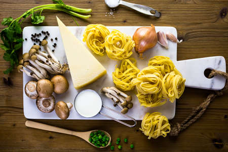 Ingredients for preparing fettuccine with creamy mushroom sauce.の写真素材