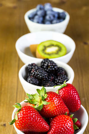Organic fresh fruit in round bowls on wood table.の写真素材