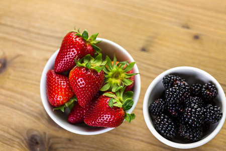 Organic fresh fruit in round bowls on wood table.の写真素材