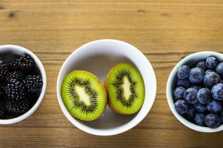 Organic fresh fruit in round bowls on wood table.の写真素材