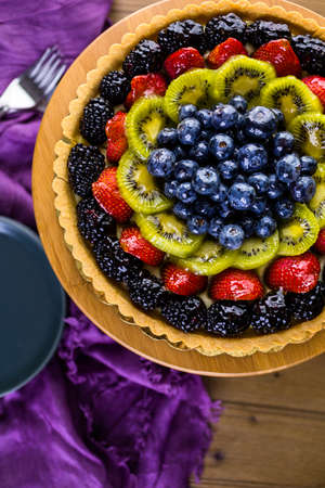 Fresh fruit tart on cake stand on wood table.の写真素材