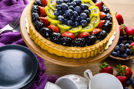 Fresh fruit tart on cake stand on wood table.の写真素材