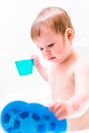 Baby girl having a good time during the bath time.