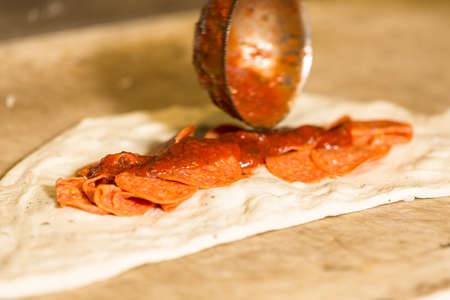 Preparing pepperoni calzone with pizza sauce and mozzarella cheese.の写真素材