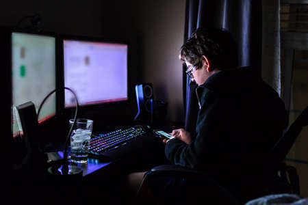 Teenager boy on computer in his room late at night.の写真素材