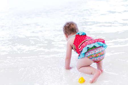 Cute toddler girl enjoying playing in the water in indoor swimming pool.の写真素材