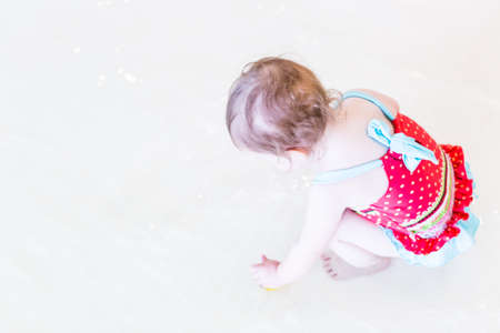 Cute toddler girl enjoying playing in the water in indoor swimming pool.の写真素材