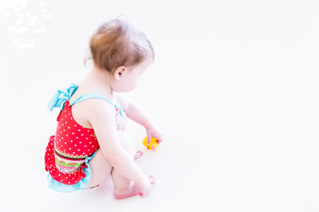 Cute toddler girl enjoying playing in the water in indoor swimming pool.の写真素材