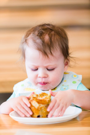 Little cute girl eating muffin at the restaurant.の写真素材