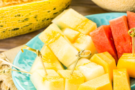 Variety of organic melons sliced on wood table.の写真素材