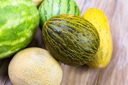 Variery of organic melons on wood board.