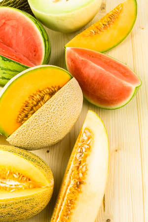 Variety of organic melons sliced on wood table.の写真素材