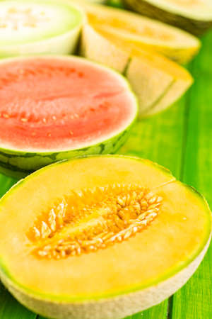 Variety of organic melons sliced on wood table.の写真素材