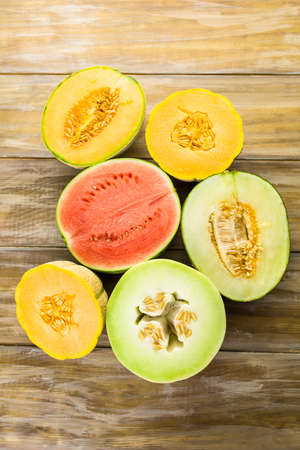 Variety of organic melons sliced on wood table.の写真素材