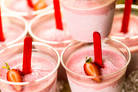 Homemade strawberry popsicles made in plastic cups.の写真素材