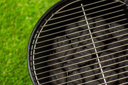 Small round charcoal grill ready for grilling at the summer picnic.の写真素材