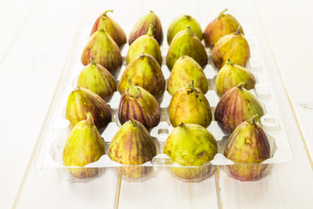 Organic California figs in plastic crate on wood table.の写真素材