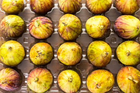 Organic California figs in plastic crate on wood table.の写真素材