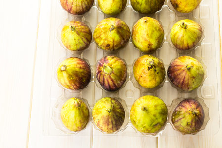 Organic California figs in plastic crate on wood table.の写真素材