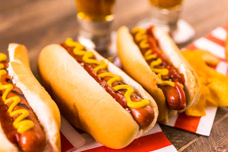 Grilled hot dogs with mustard and ketchup on the table with draft beer.の写真素材
