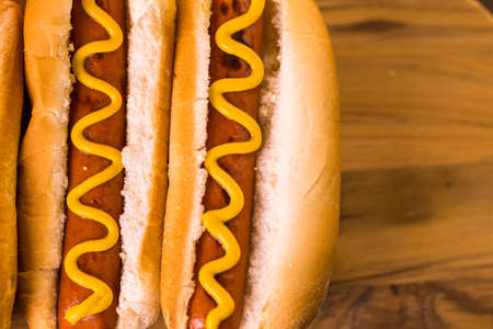 Grilled hot dogs on a white hot dog buns with mustard and ketchup.の写真素材