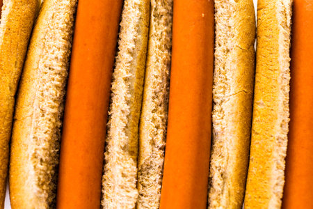 Traditional hot dogs on a white hot dog bun on a white background.