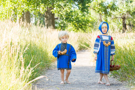 Russian children in traditional Russian costumes playing in the forest.