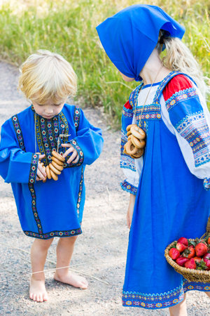 Russian children in traditional Russian costumes playing in the forest.