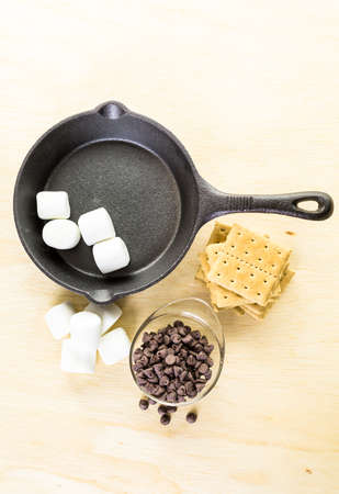 Ingredients smores dip prepared with large marshmallows in cast iron pan.の写真素材