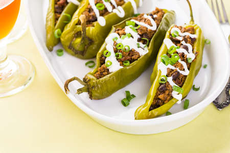 Chipotle beef & bean stuffed chile peppers garnished with sour cream and scallions.の写真素材