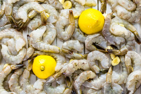Raw peeled shrimp with tails with lemon ready for roasting.の写真素材