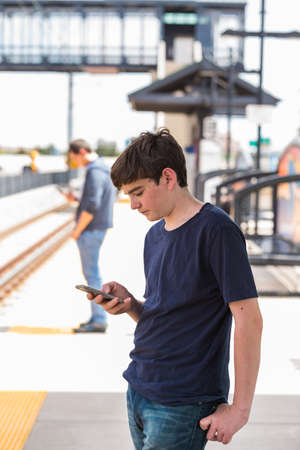 Teenage boy at the lightrail station in urban area.の写真素材